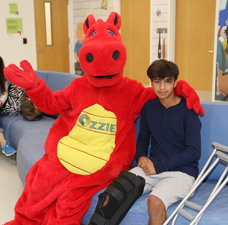 OIC’s mascot Ozzie sits with the new Urgent Care Center’s first patient, Bryan